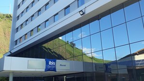 A modern hotel building with a glass facade, a blue awning, and a sign for 'ibis budget'. - ibis budget Muriae (Muriae)