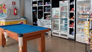 A pool table in a room with shelves stocked with snacks and a refrigerator. - ibis budget Muriae (Muriae)