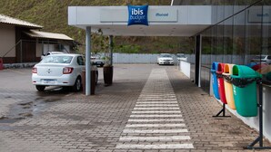 A hotel entrance with a covered walkway, a sign for ibis budget hotels, and a row of colorful trash bins. - ibis budget Muriae (Muriae)