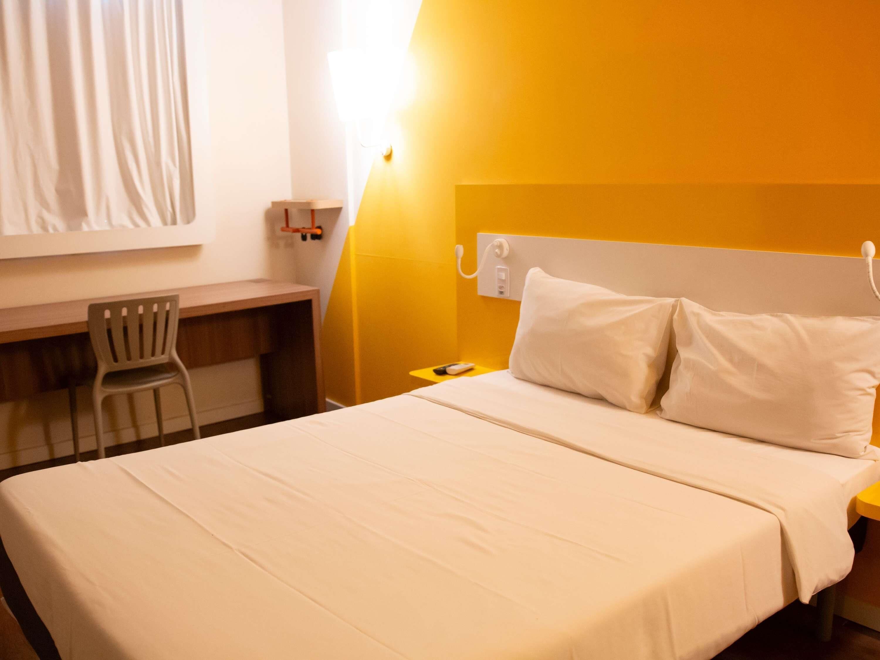Une chambre d’hôtel comprenant un lit, un bureau, une chaise et une table de chevet.