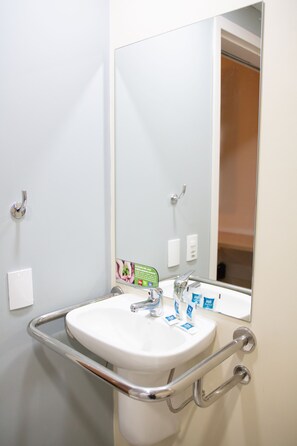A bathroom with a white sink, a mirror, and a handrail. - ibis budget Muriae (Muriae)