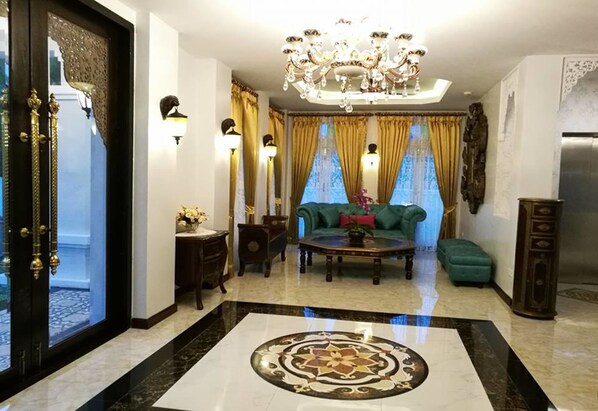 A luxurious living room with a chandelier, a sofa, a coffee table, and a patterned floor.