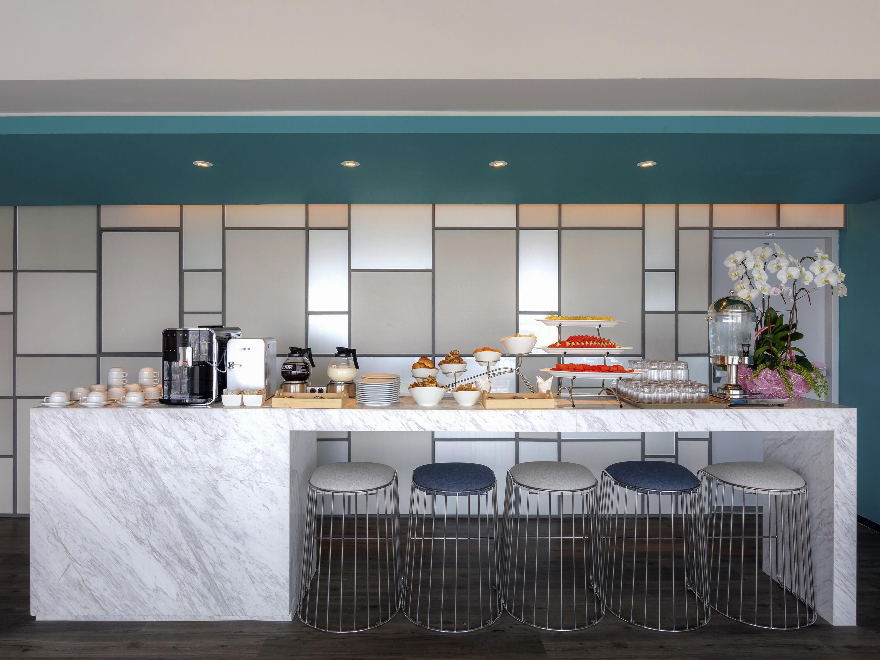Une cuisine moderne dotée d’un plan de travail en marbre, d’une machine à café et d’un coin bar avec des tabourets.
