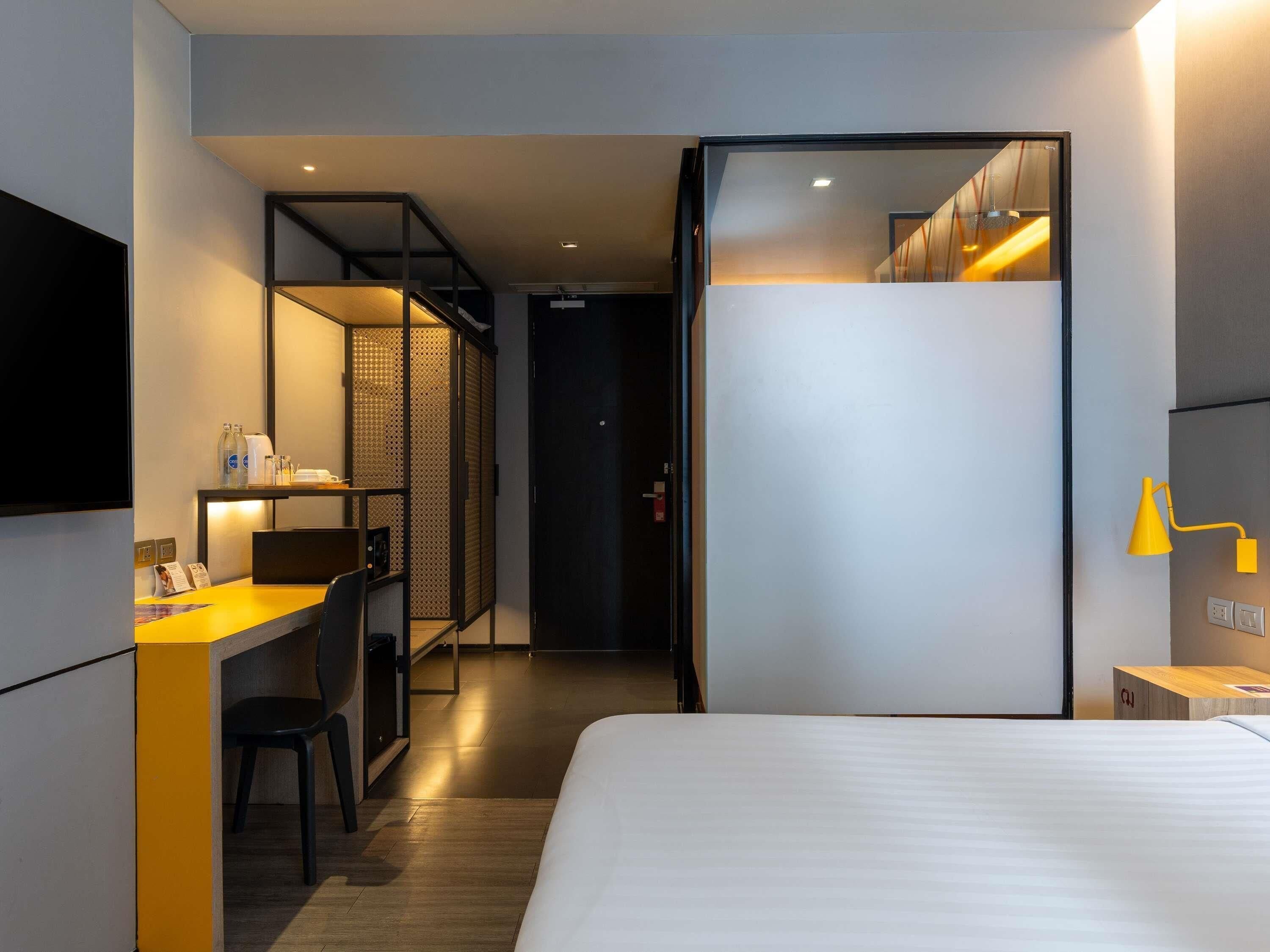 Une chambre d’hôtel avec un lit, un bureau et une chaise, une télévision et un miroir.