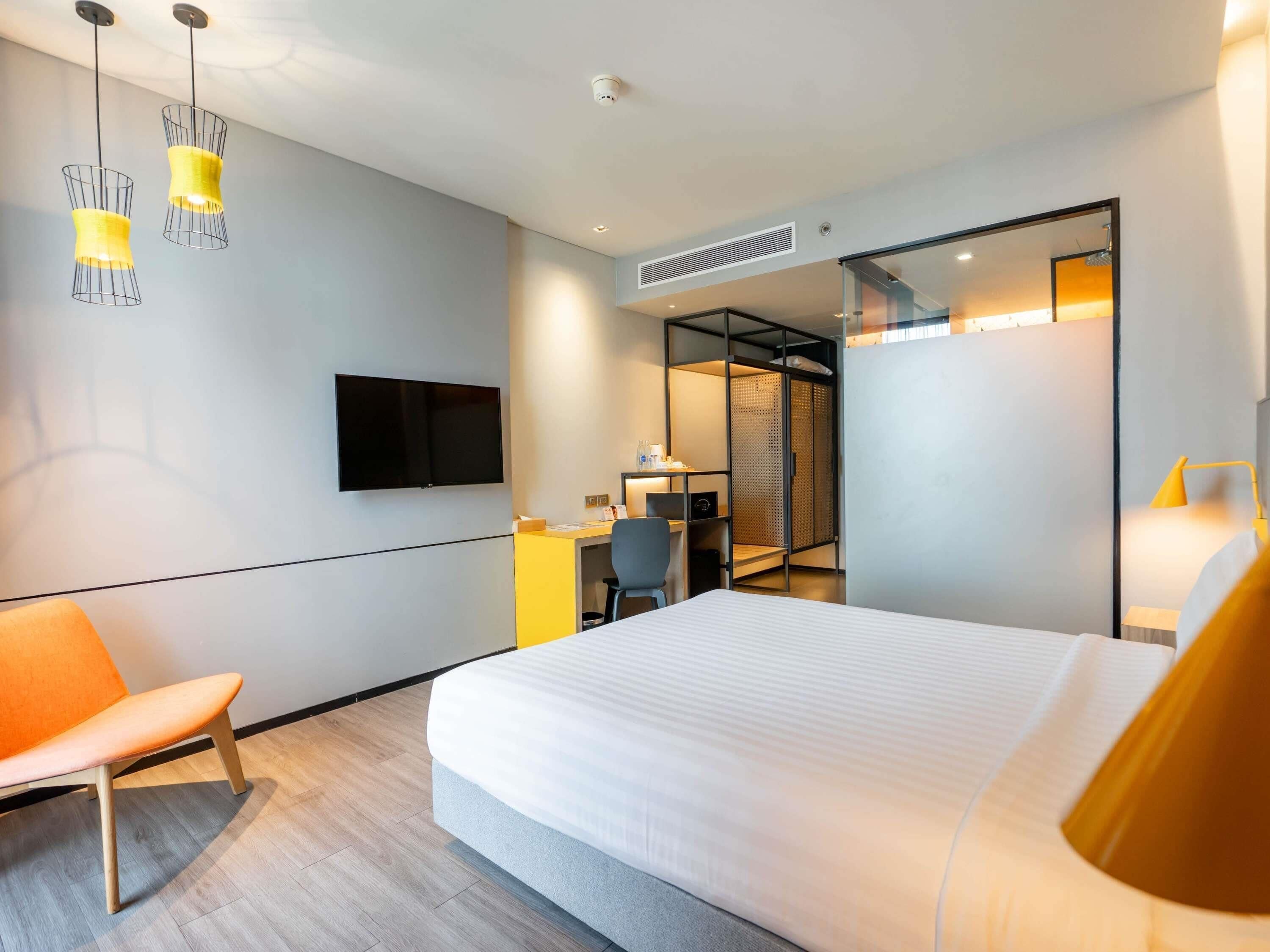Ein Hotelzimmer mit einem Bett, einem Schreibtisch, einem Stuhl, einem Fernseher und einem Kleiderschrank.