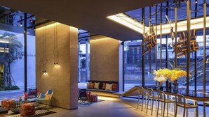 A modern interior with a sofa, chairs, a staircase, and a view of the outside. - ibis Styles Bangkok Sukhumvit Phra Khanong (Bangkok)