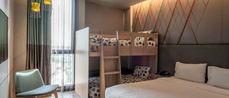 A bedroom with a bunk bed, a single bed, a chair, a desk, and a window with curtains.