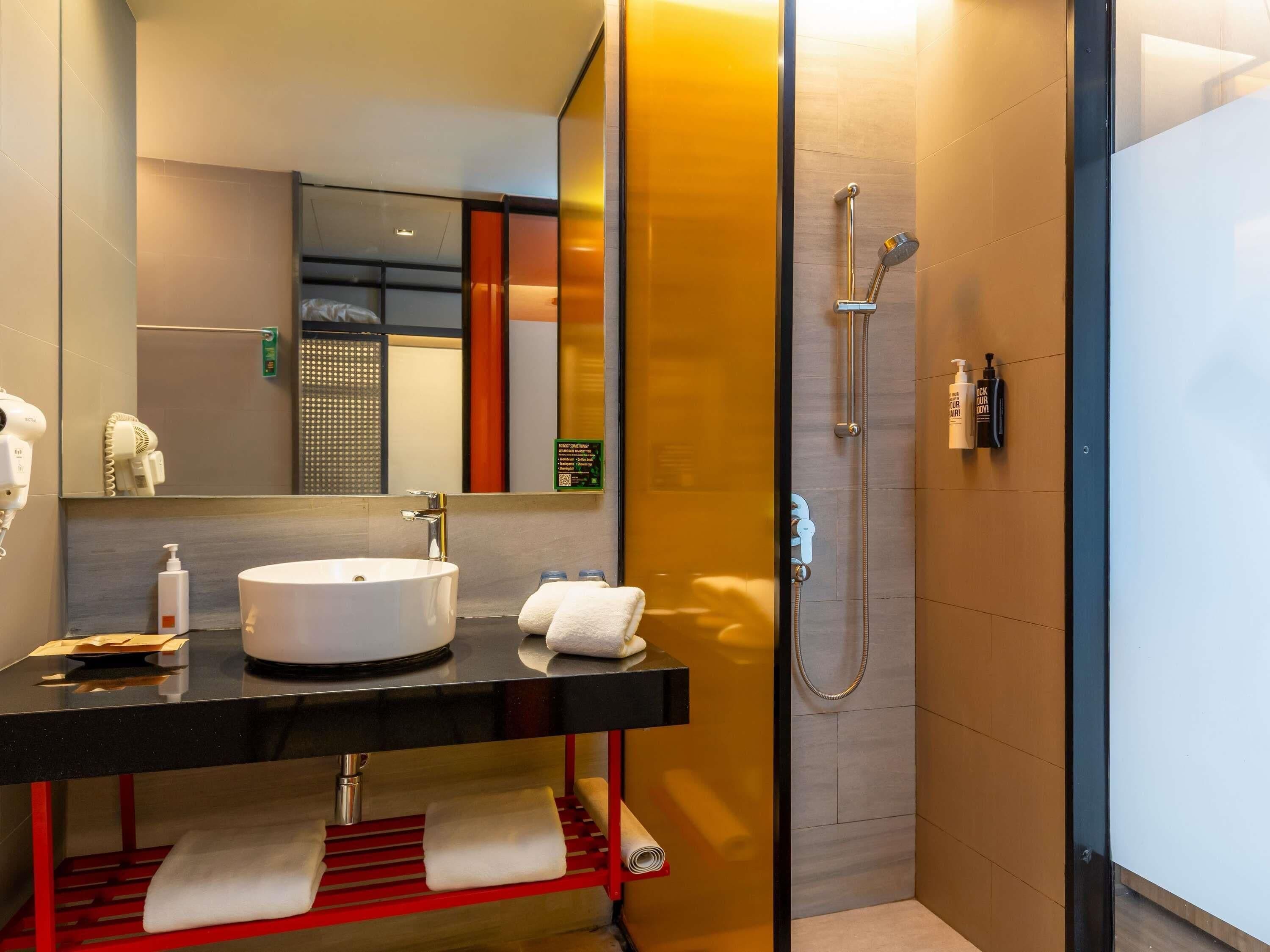 A modern bathroom with a sink, mirror, towel rack, and shower.