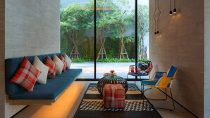 A modern living room with a blue sofa, colorful cushions, a round coffee table, and a yellow and blue chair. - ibis Styles Bangkok Sukhumvit Phra Khanong (Bangkok)