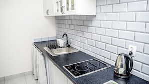 A modern kitchen with white cabinets, a black countertop, a sink, and a kettle. - AP-Apartments Marszałkowska No. 53 (Warsaw)