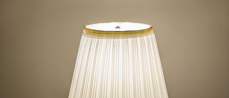 A table lamp with a pleated shade on a white table with a red placemat.