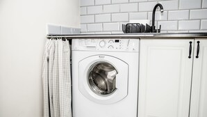 A compact, white washing machine in a modern kitchen with white cabinets and a tiled backsplash. - AP-Apartments Marszałkowska No. 53 (Warsaw)