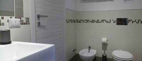 Un baño con lavabo, bidé, inodoro y un perchero para toallas.