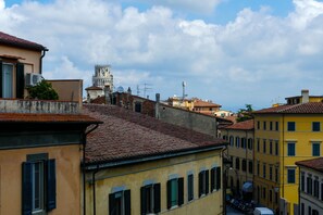 A street view with buildings, a prominent tower, and a clear sky. - Gialel Pisa (Pisa)