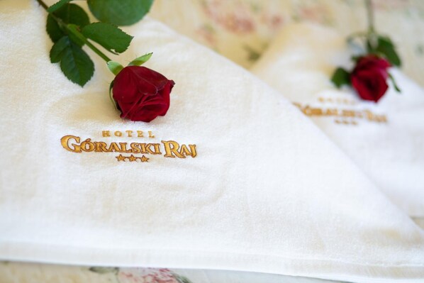 A hotel towel with the name "HOTEL GORALSKI RAJ" and a red rose.