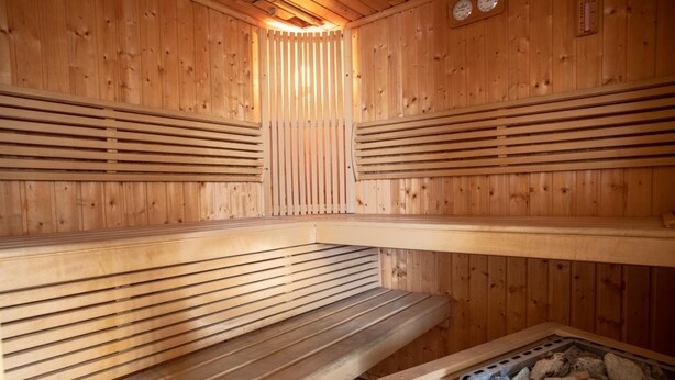A sauna with wooden benches and a stone heating element. - Hotel Góralski Raj (Nowy Targ)