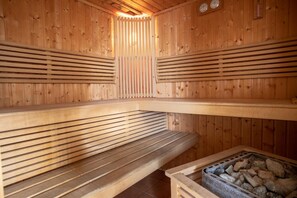Una sauna con bancos de madera y un elemento calefactor de piedra.