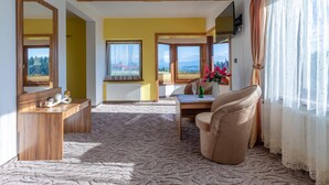 A room with a wooden ceiling, a large window with a view of the mountains, a dining table with chairs, and a sofa. - Hotel Góralski Raj (Nowy Targ)