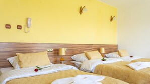 A hotel room with two beds, yellow walls, wooden headboard, bedside lamps, and a telephone on the wall. - Hotel Góralski Raj (Nowy Targ)