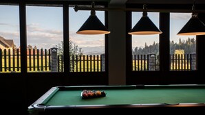 A pool table with a view of a wooden fence and trees through large windows. - Hotel Góralski Raj (Nowy Targ)