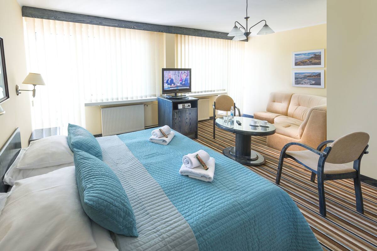 A hotel room with a bed, a desk, a chair, and a television.