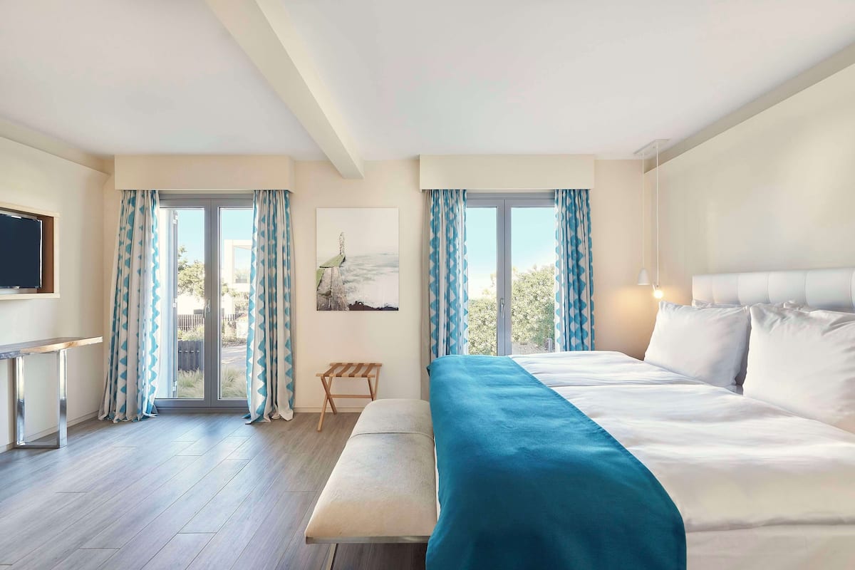 Habitación de hotel con una cama grande, un banco, un escritorio y una televisión.