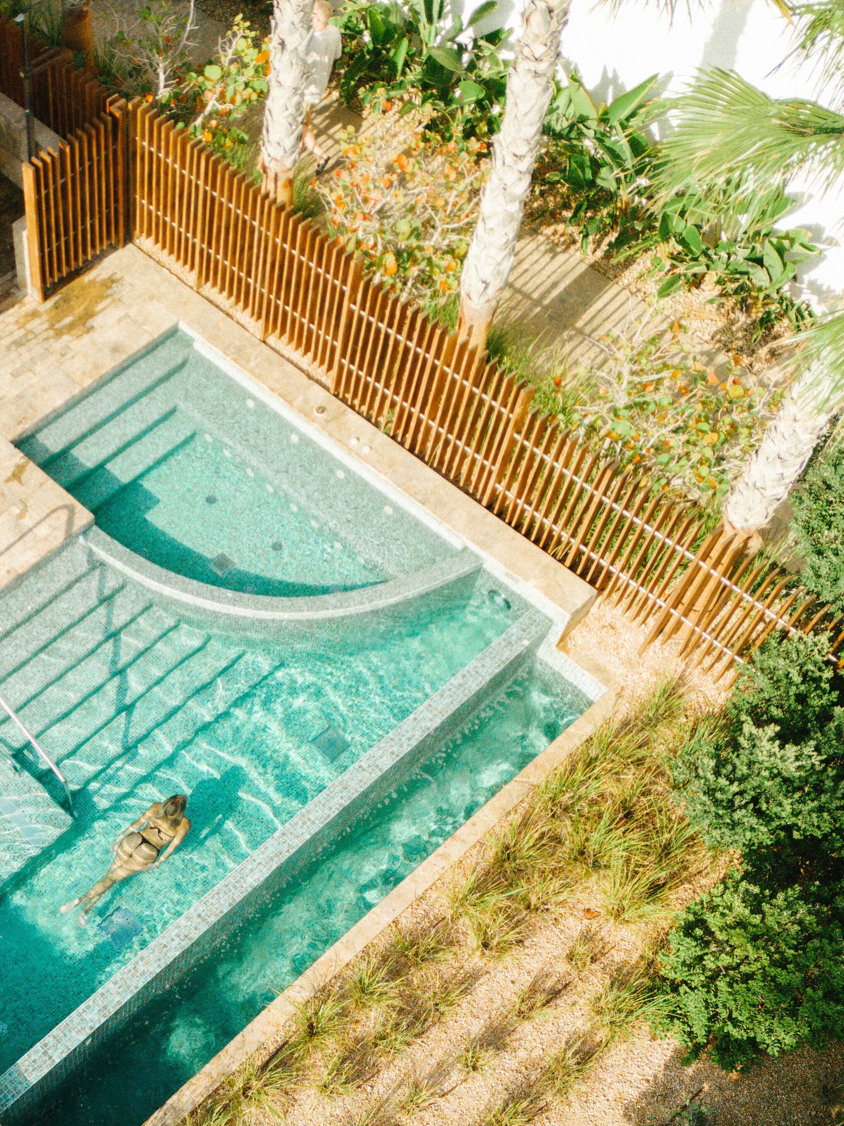 Ein Schwimmbad mit Holzterrasse und umgebender Bepflanzung.