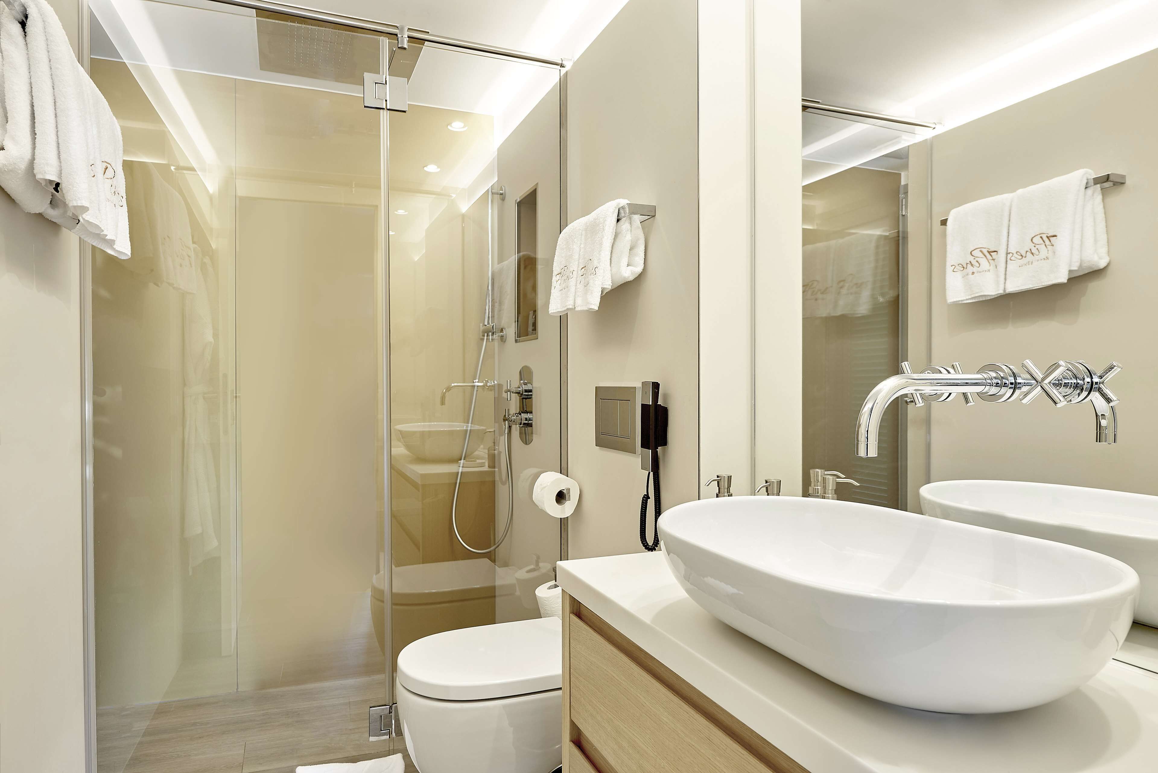 Un baño moderno con ducha de mampara de vidrio, dos lavamanos y un inodoro.