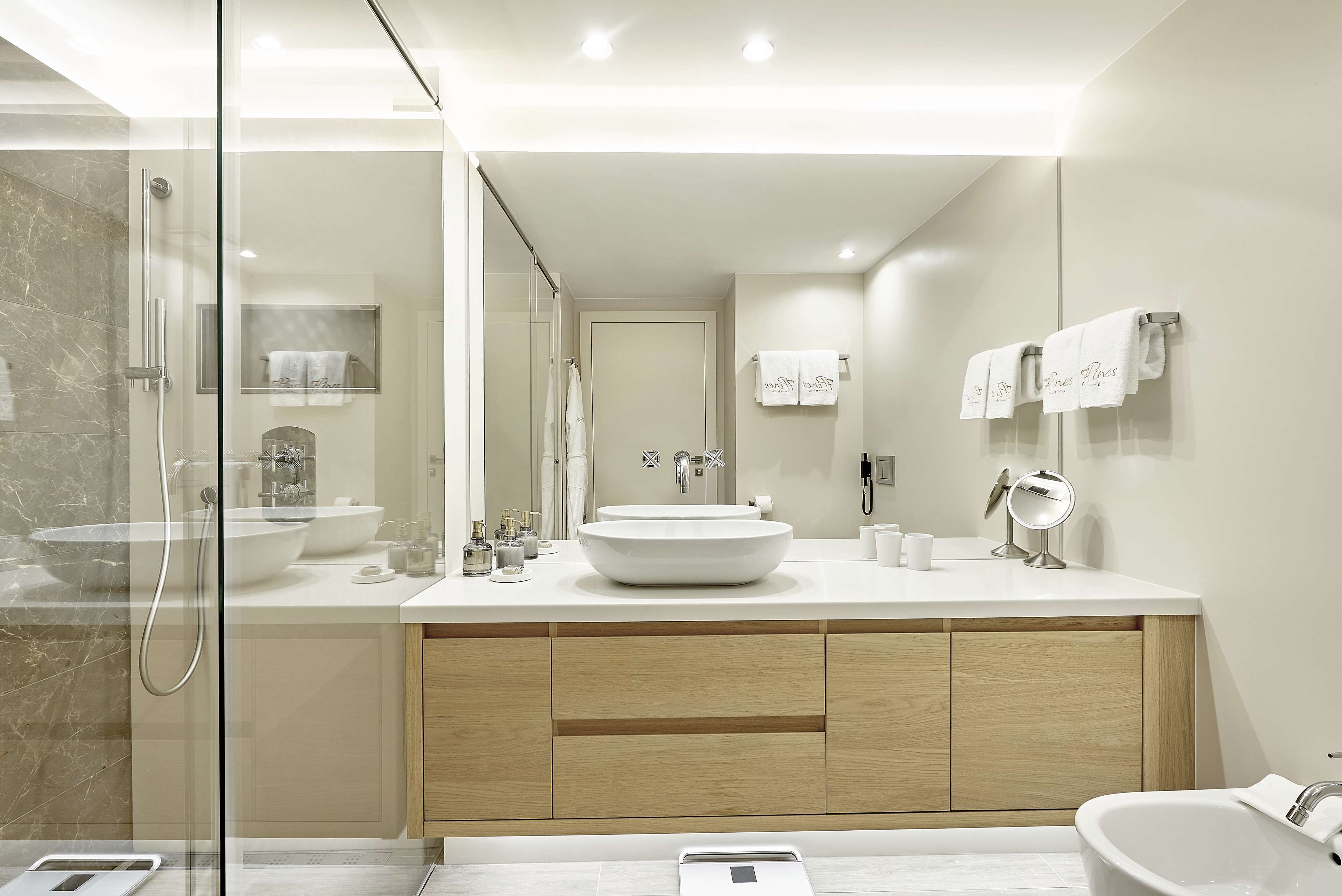 Un baño moderno con ducha de vidrio, un lavamanos grande de color blanco y una bañera independiente.
