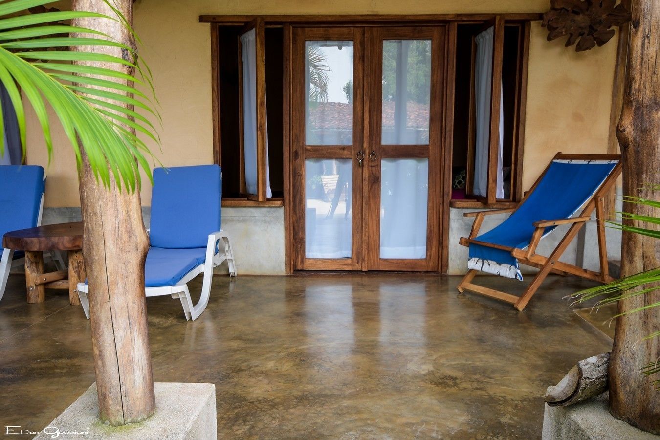Un espace extérieur abrité avec des chaises bleues et une table en bois.