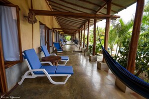 A covered outdoor seating area with blue lounge chairs and a hammock. - Casa Lajagua (Pedasí)