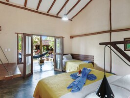 Una habitación con dos camas, una hamaca y vista a un espacio exterior con una estructura de madera.