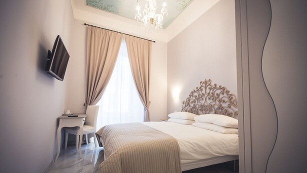 A bedroom with a bed, a TV mounted on the wall, a chair, and a desk. - The golden keys rome (Rome)