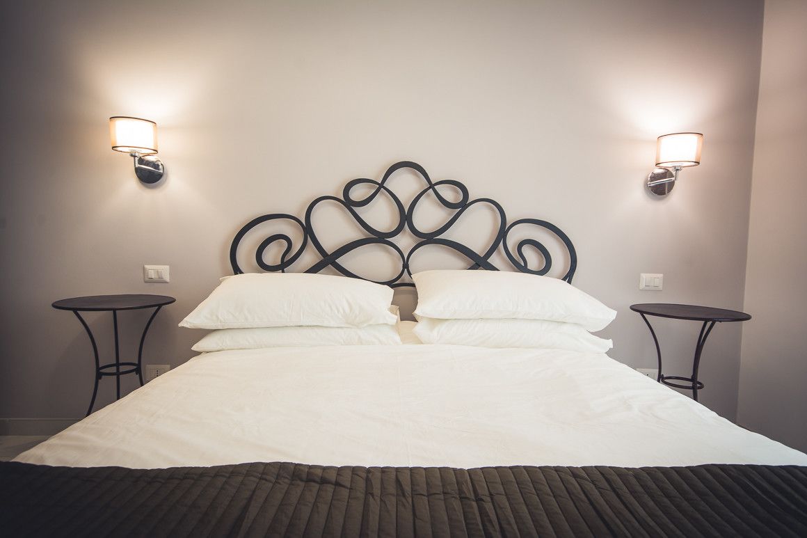 A neatly made bed with a decorative headboard, two bedside tables, and wall-mounted lamps.