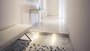 A hallway with a white bench, a console table with a mirror, and a patterned floor. - The golden keys rome (Rome)