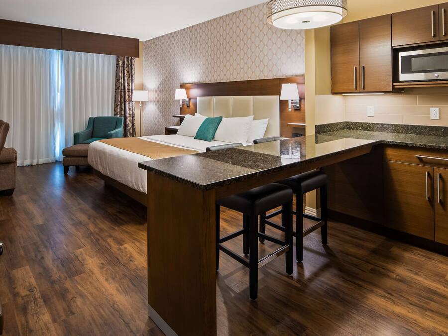 Habitación de hotel con cama, escritorio, silla, kitchenette y baño.