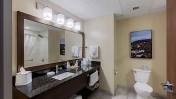 Un baño de hotel con un espejo grande, dos lavamanos, un inodoro y una ducha.