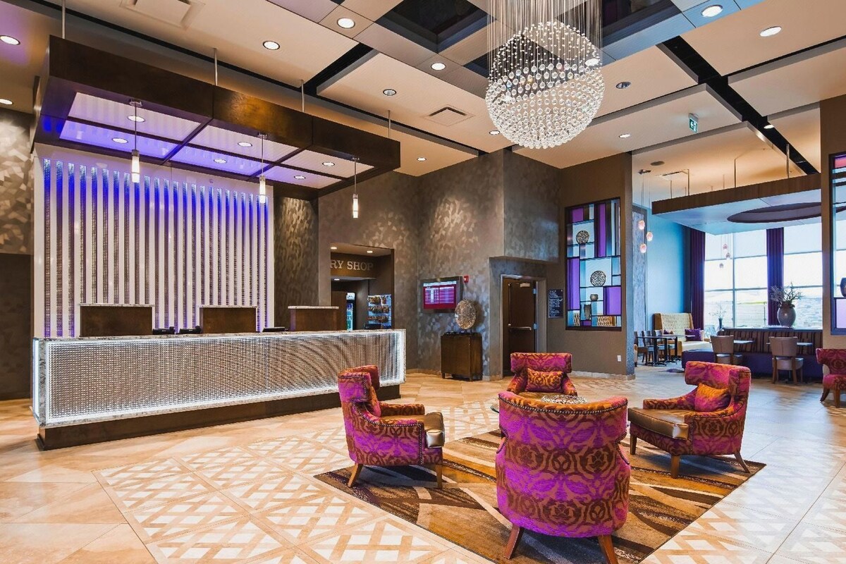 Vestíbulo de hotel con mostrador de recepción, baldosas de piso estampadas, un candelabro y una zona de estar.