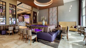 Un moderno vestíbulo de hotel con zona de estar, bar y recepción.