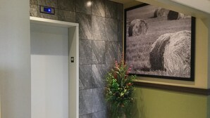 A lobby with a marble wall, a framed photograph, and a potted plant. - Super 8 by Wyndham Hardisty (Hardisty)