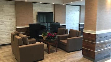 Een moderne woonkamer met een flatscreen televisie, comfortabele banken, een houten salontafel en een decoratieve plant.