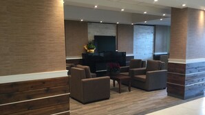 A modern lobby with wooden paneling, a flat-screen TV, and comfortable seating. - Super 8 by Wyndham Hardisty (Hardisty)