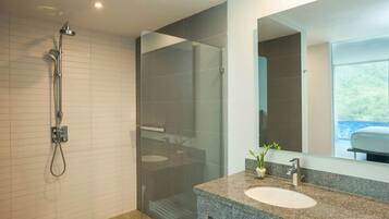 A modern bathroom with a glass shower enclosure, a granite countertop sink, and a large mirror.