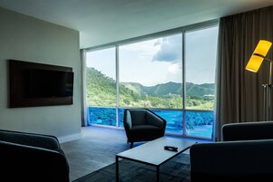 A modern hotel room with a large window offering a view of a mountainous landscape.