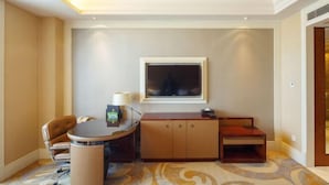 A hotel room with a round table, a single chair, a wooden cabinet, and a television mounted on the wall. - Juva Grand Hotel (Hohhot)