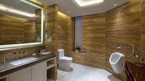 A modern bathroom with a large mirror, a sink, a toilet, and a urinal. - Juva Grand Hotel (Hohhot)
