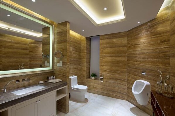 A modern bathroom with a large mirror, a sink, a toilet, and a urinal.