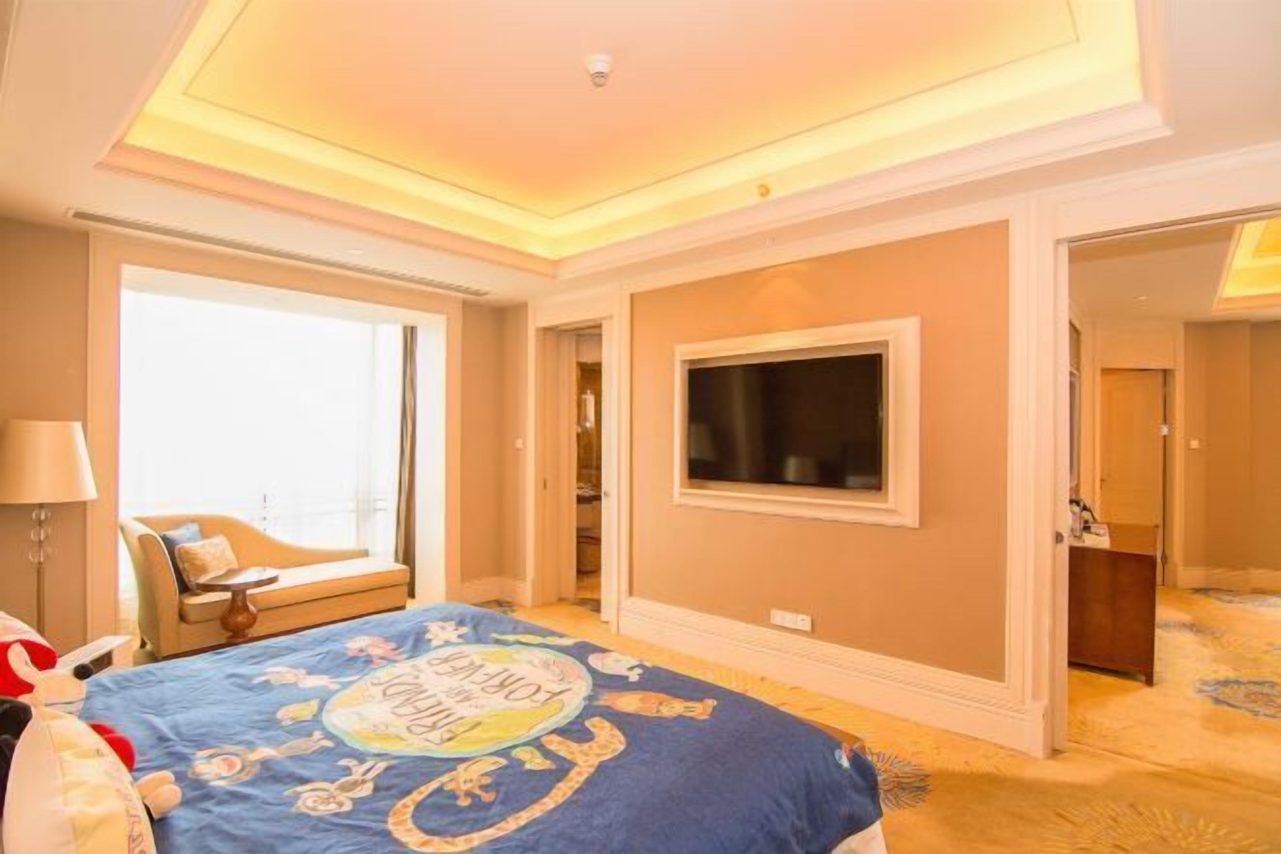 A hotel room with a large bed, a television, and a view of the city.