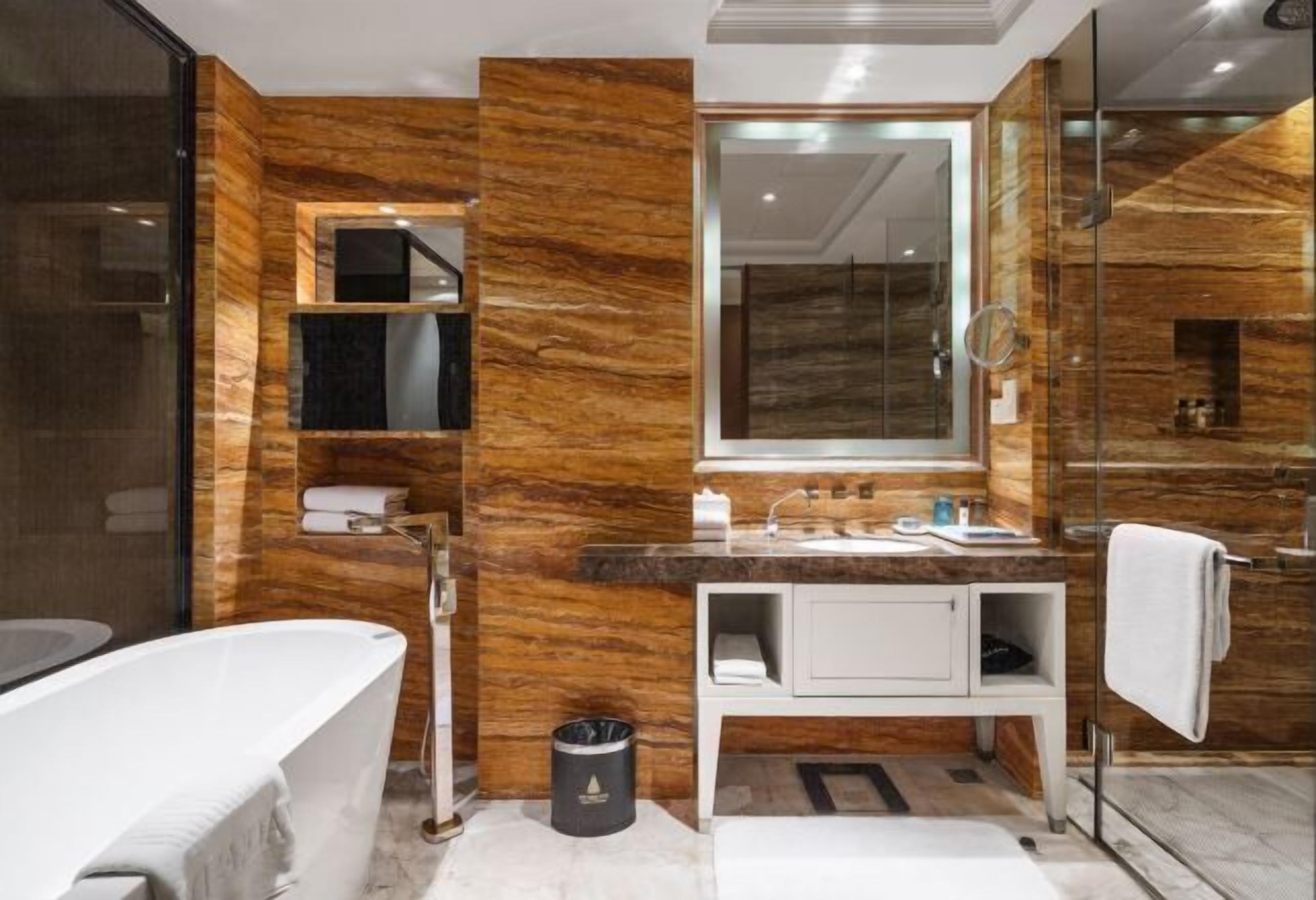 Een moderne badkamer met een vrijstaand bad, een wastafel met spiegel, en een douchecabine met glazen wanden.