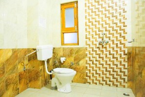 Une salle de bain avec des toilettes, une douche et une fenêtre.
